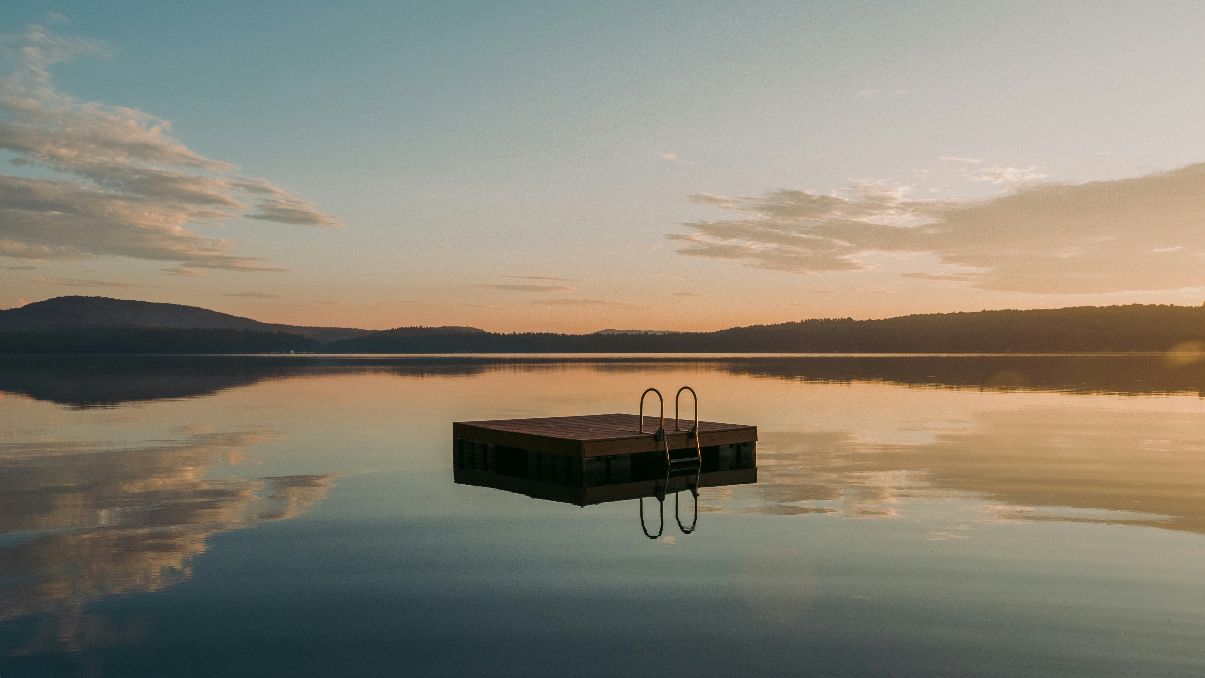 A wooden float is lit by the sunrise on a lake in Maine.